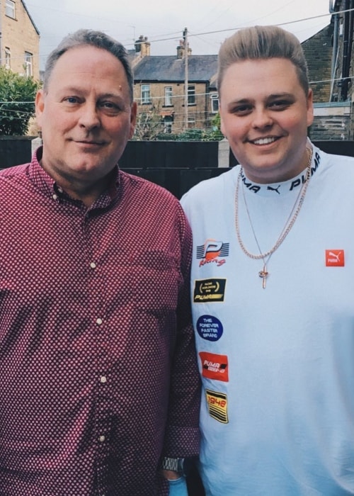 Nick Crompton sporting a white outfit while posing with his father in December 2017